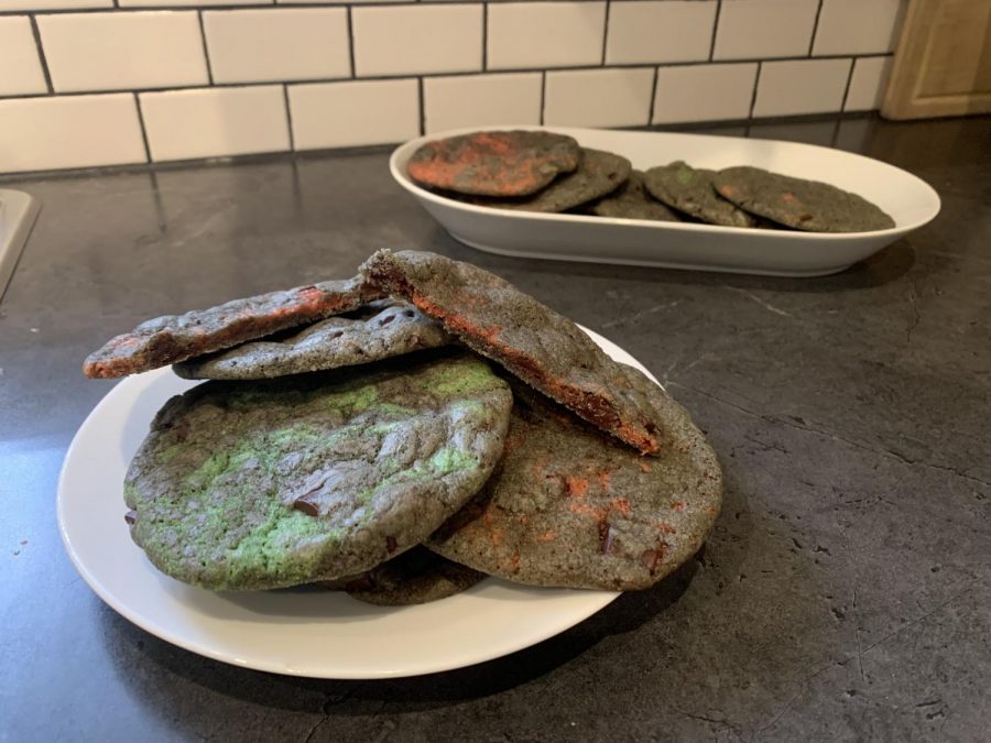Magma cookies sitting on two plates; they are black with red, green, and purple colored insides