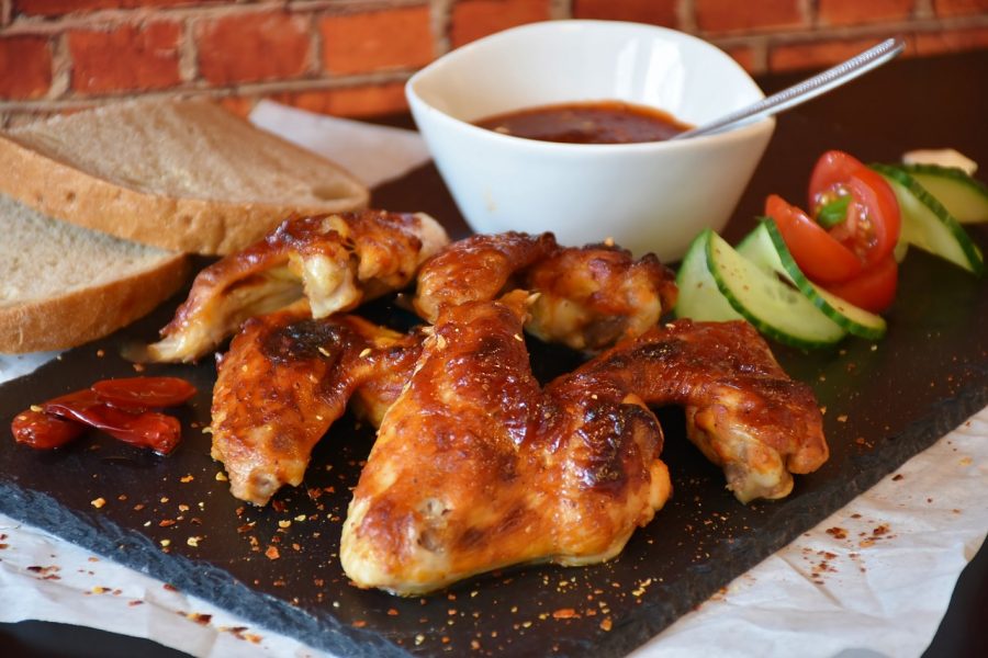 A neatly prepared plate of chicken wings served with vegetables, bread and dipping sauce. 