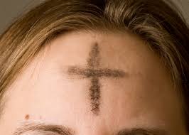 A girl gets marked on her forehead with the cross for Ash Wednesday.