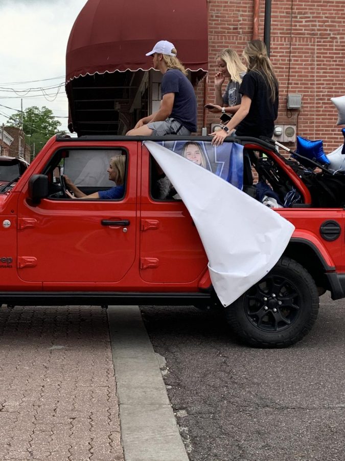 Seniors Paige Robinson, Brennan Strubberg and Claire Strubberg ride on the top of a car in the parade.