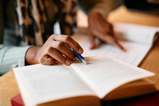 Close-up of a female student learning from books in a library.